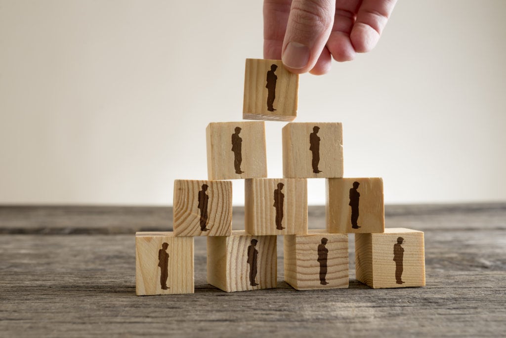 Man stacking a tower of wood blocks with human silhouettes, human resources and management concept.