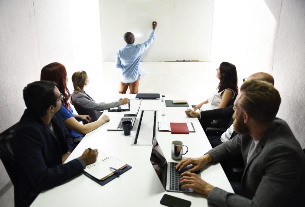 A picture of coworkers in a boardroom around a table.