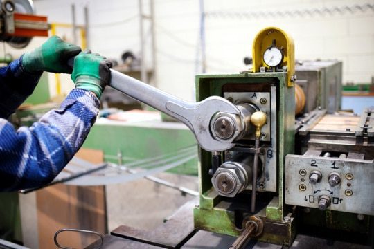 An image of a factory maintenance worker adjusting a machine as part of IIoT connectivity.